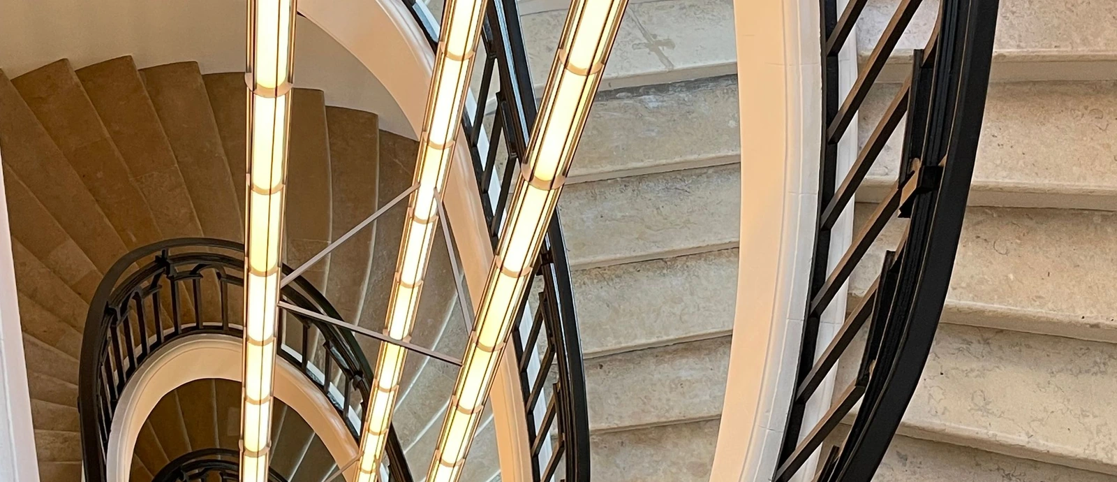 Courbes d’un escalier parisien en pierre claire et garde-corps aux lignes épurées