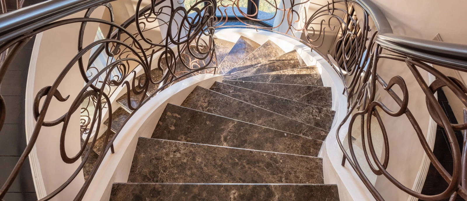 Courbes d’un escalier en marbre et détail de son garde-corps