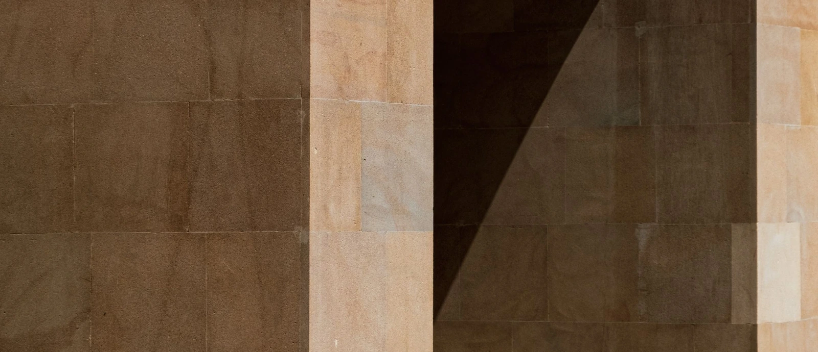 Détail d’une arche en pierre beige et de sa lumière naturelle